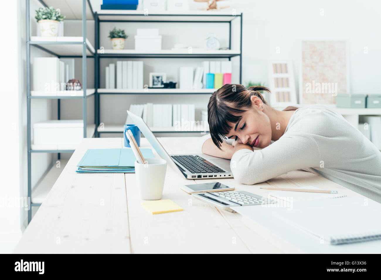 Giovani stanchi donna alla scrivania in ufficio a dormire con gli occhi chiusi, la privazione di sonno e di vita stressante concept Foto Stock