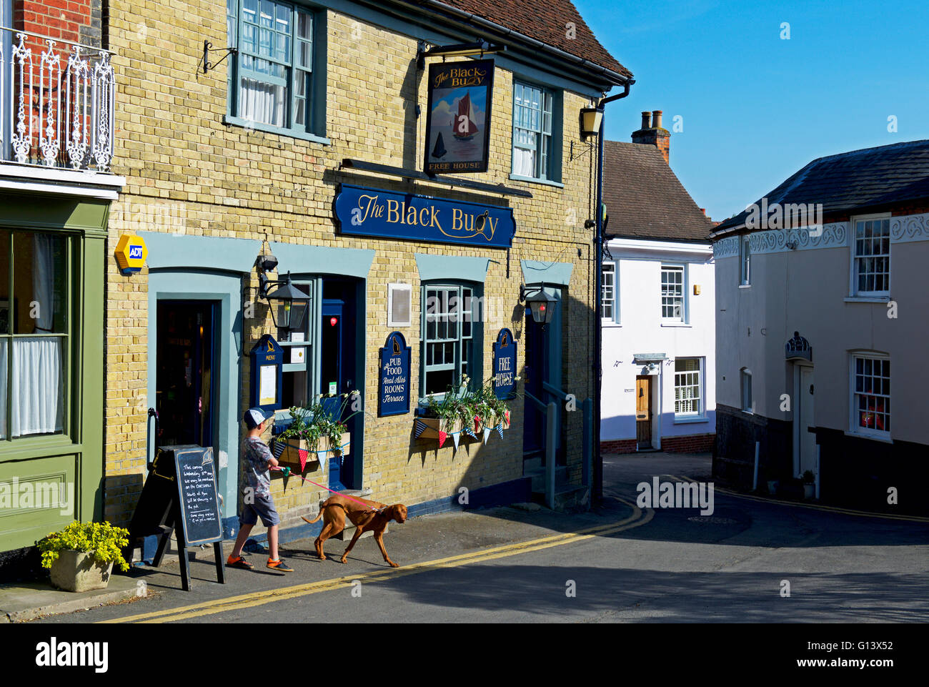 Ragazzo con cane fuori la boa nero pub in Wivenhoe, Essex, Inghilterra, Regno Unito Foto Stock
