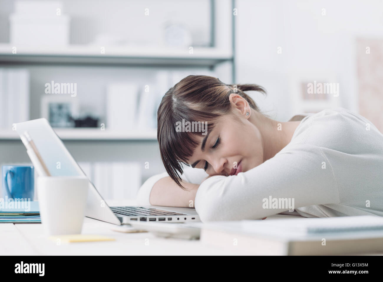Giovani stanchi donna alla scrivania in ufficio a dormire con gli occhi chiusi, la privazione di sonno e di vita stressante concept Foto Stock