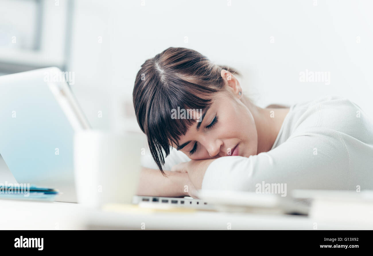 Giovani stanchi donna alla scrivania in ufficio a dormire con gli occhi chiusi, la privazione di sonno e di vita stressante concept Foto Stock