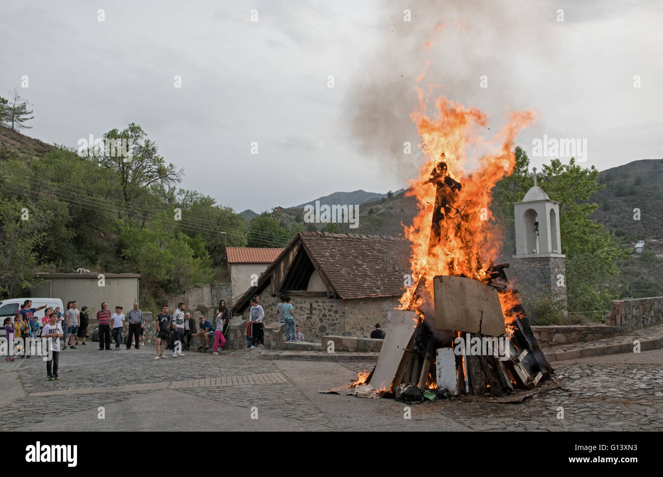 Le persone al di fuori di una chiesa con fuoco Giuda Iscariota effige che tradiscono Gesù Cristo per la Pasqua di Cipro Foto Stock