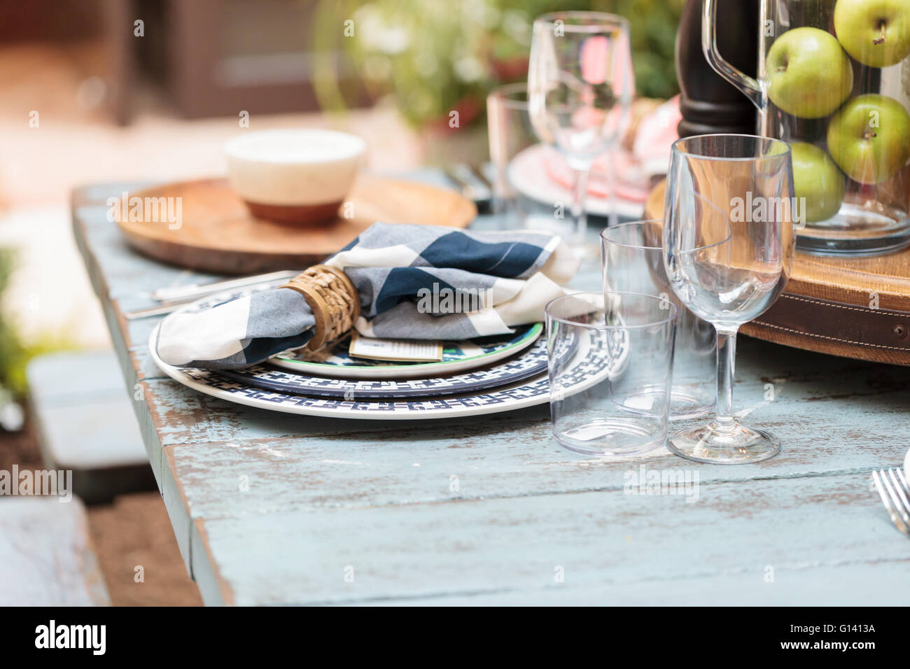 Agriturismo Rustico posto impostazione di bianco e blu con piastre, tovaglioli e chiaro bicchieri di vino in un paese invecchiato tavolo su un patio in Foto Stock