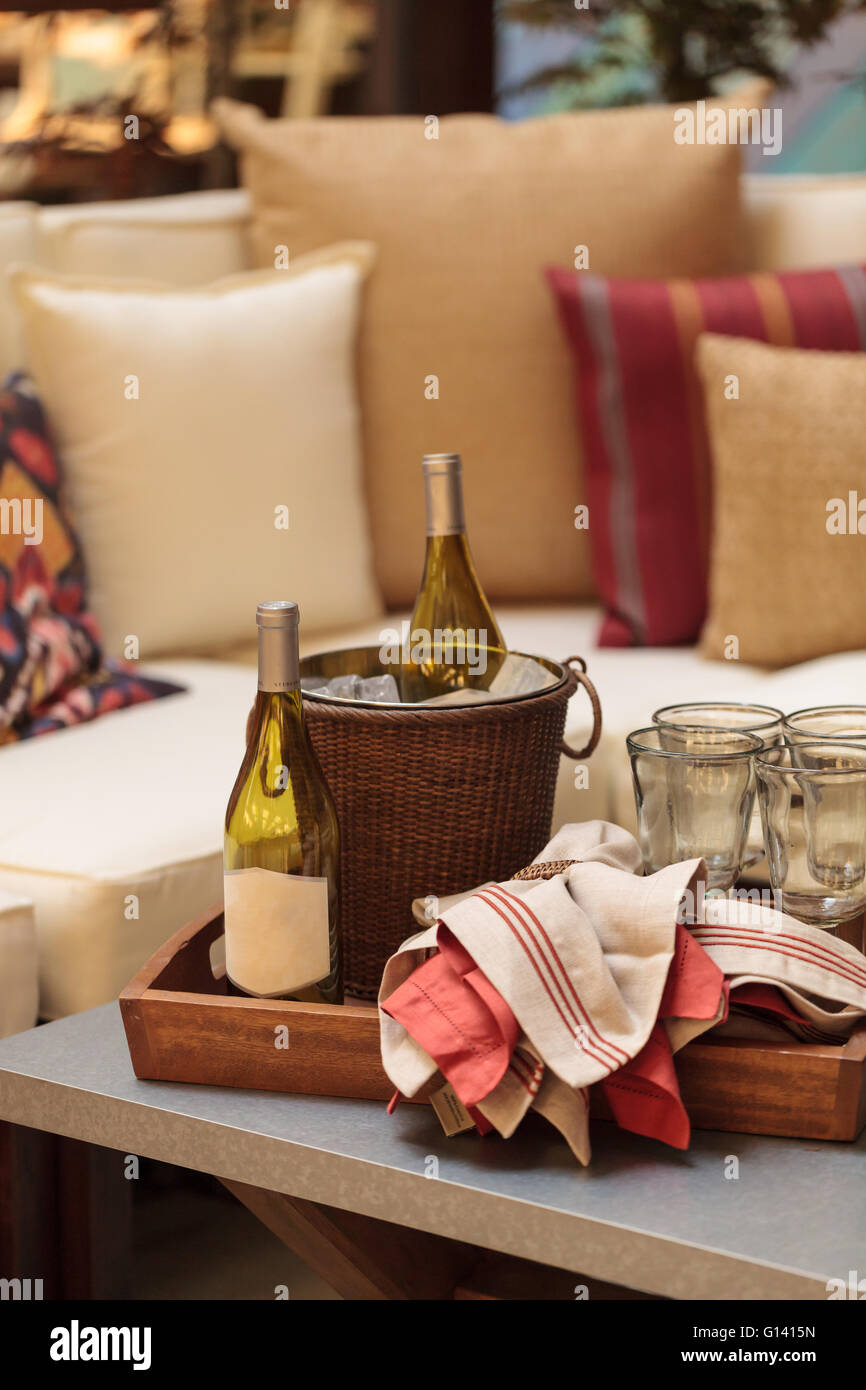 Secchiello per ghiaccio, bottiglia di vino bianco, rosso e bianco di tovaglioli, bicchieri di vino sul vassoio su un patio in stile rustico tavolo in estate. Foto Stock
