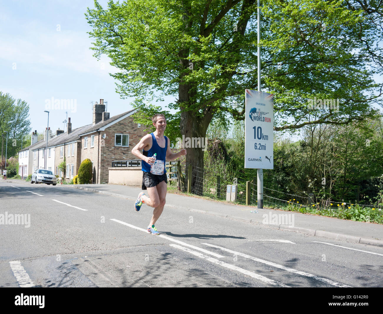 Westwick, Cambridgeshire, Regno Unito. 8 Maggio, 2016. I corridori passano attraverso il villaggio di Westwick a 10K punto delle ali della vita mondo viene eseguito avendo iniziato a Cambridge a temperature di circa 26 gradi C. Guide in 35 sedi in tutto il mondo ha iniziato esattamente nello stesso momento ed eseguire il più a lungo possibile. Non c'è un traguardo e un "catcher car" (guidato da David Coulthard nel Regno Unito) inizia a trenta minuti dopo la gara inizia e lentamente la velocità fino a quando ognuno è superato. L'ultima persona che esegue è il vincitore globale. Credito: Julian Eales/Alamy Live News Foto Stock