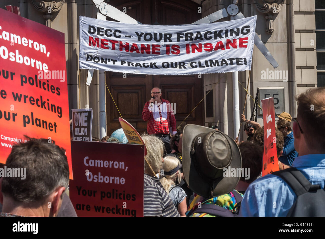 Londra, Regno Unito. 8 maggio 2016. I manifestanti hanno marciato indietro lungo Whitehall contro il governo del Regno Unito hanno il backtracking su energia pulita, che ha visto la caduta di isolamento di borse e paralizzare la nostra energia verde programmi mentre il clima di supporto-wrecking fracking e progetti di biomassa lungo con proponendo massivily inquinanti e inutili su strada e su pista progetti.Un altoparlante al DECC sotto un banner 'DECC - Il vostro Fracking metano è folle - Non Frack il nostro clima!. Peter Marshall / Alamy Live News Foto Stock