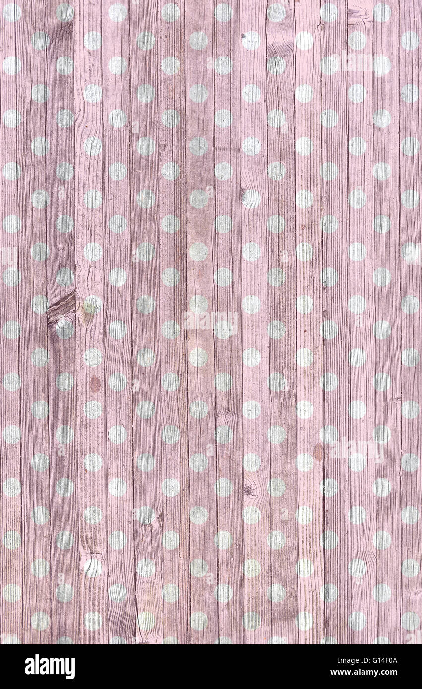 Rosa sbiadito e bianco polka dot pattern su weathered legno antico. Foto Stock