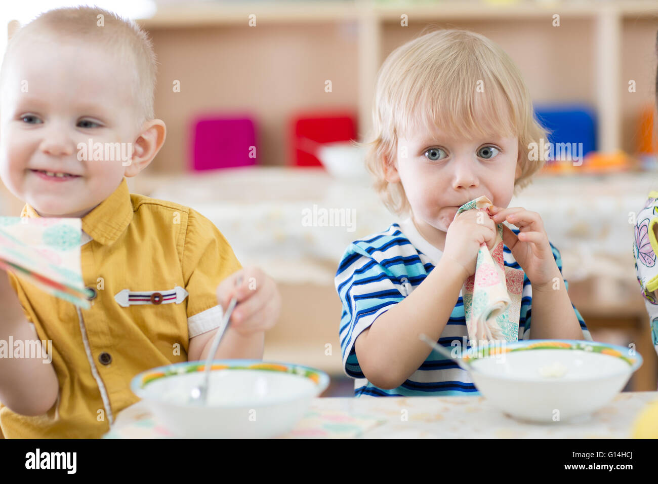 Divertente i bambini a mangiare in una scuola materna Foto Stock