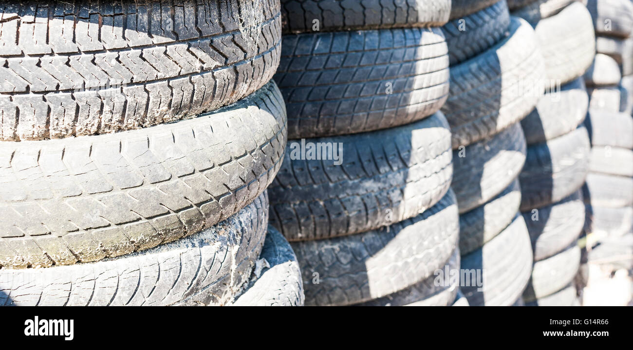 Vecchi pneumatici usati impilati con pali alti Foto Stock