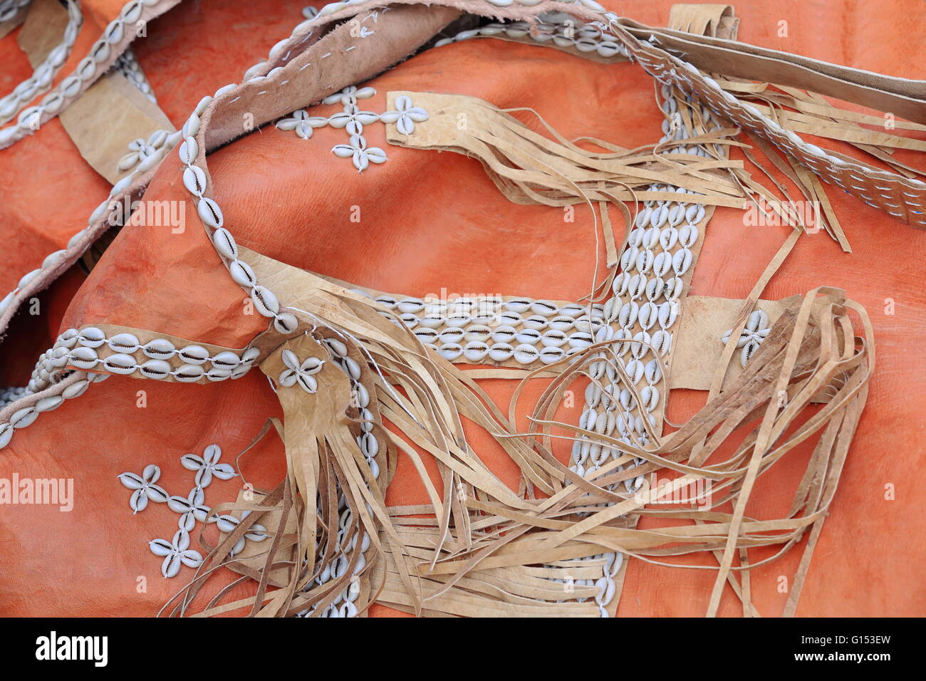 Etnici cinghie tradizionale fatta di gusci cowrie cuciti su frange Cinturini di pelle impostata sul colore arancio bucce. Mek'ele-Etiopia Foto Stock