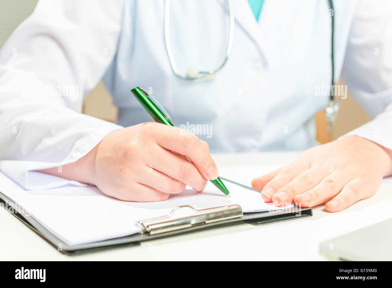 Dottore in camice bianco scrive su una prescrizione della carta Foto Stock