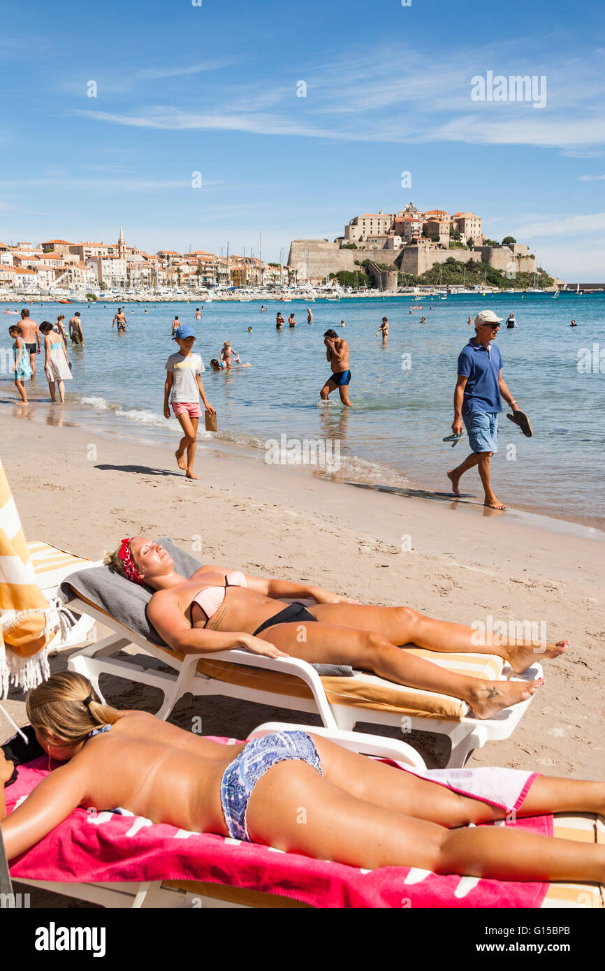 Vista della cittadella dalla spiaggia, e le giovani donne a prendere il sole, Calvi, Haute-Corse, Corsica, Francia Foto Stock