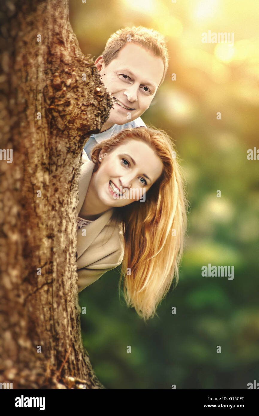 Felice coppia giovane in piedi dietro ad albero e divertirsi Foto Stock
