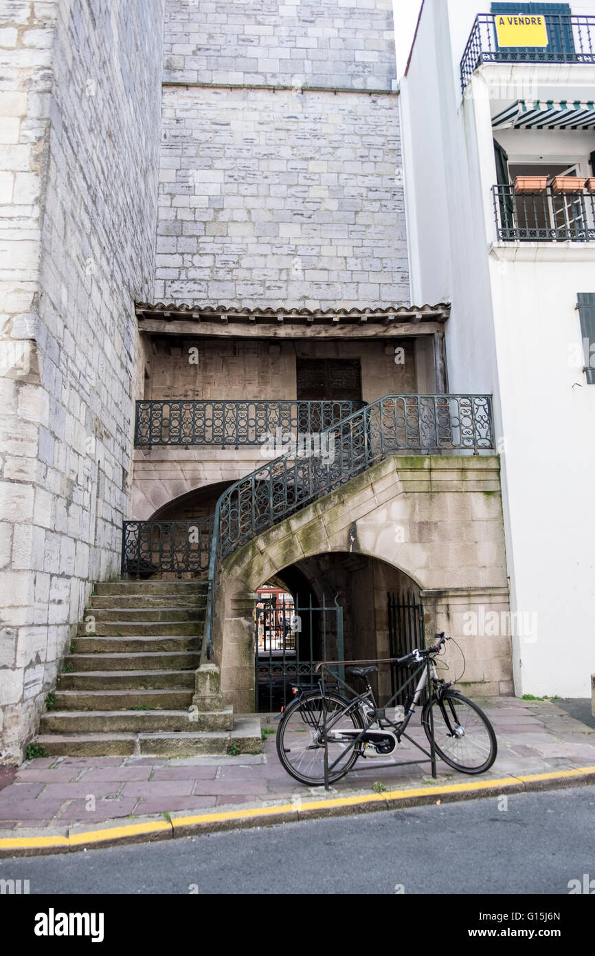 Vecchia bicicletta e scala in pietra con ringhiere in ferro battuto Foto Stock