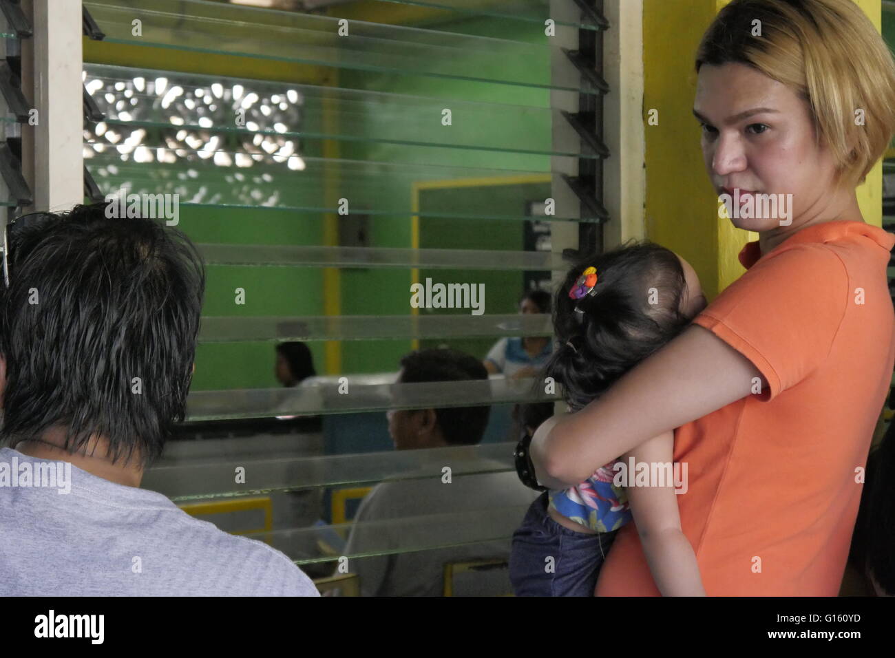 Mandaluyong, Filippine. 09 Maggio, 2016. Questo ragazzo è in attesa in linea mentre portare questo bambino dormiente. Tutti sono stanchi, sudorazione e frustrati. © George Buid/Pacific Press/Alamy Live News Foto Stock