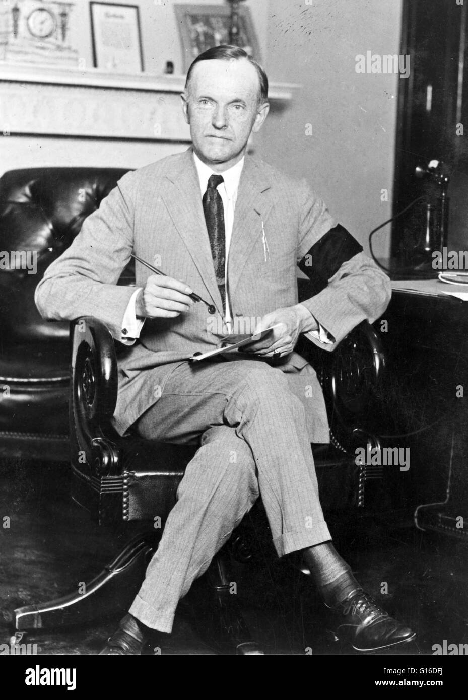 Appena giurato in President Coolidge, seduto alla scrivania, tenendo in mano carta e penna, indossa una fascia nera al braccio in lutto per il Presidente Harding. John Calvin Coolidge, Jr. (Luglio 4, 1872 - Gennaio 5, 1933) era il trentesimo Presidente degli Stati Uniti (1923-1929). Un Republ Foto Stock