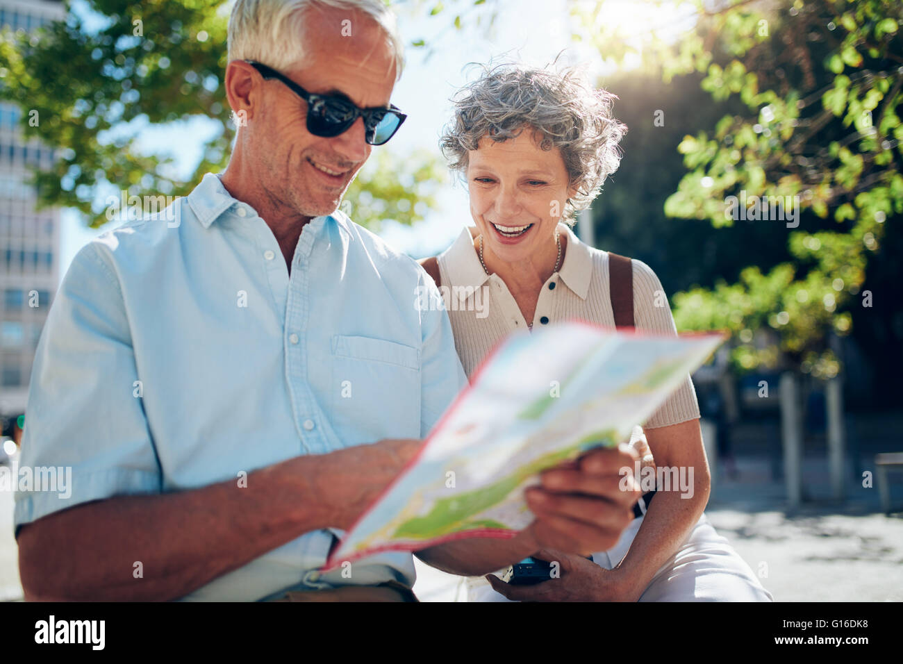 Coppia di anziani seduti all'aperto e utilizzando una mappa della citta'. Felice coppia in pensione alla ricerca di una destinazione su una mappa della città. Foto Stock