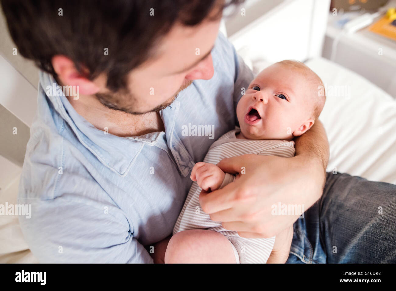 Giovane padre tenendo il suo neonato figlio, home camera da letto Foto Stock