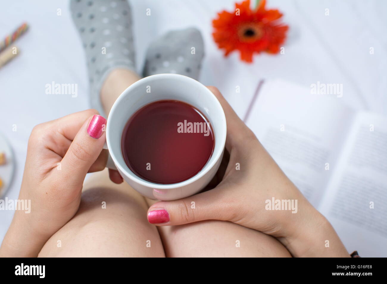 Donna che mantiene una tazza di tè nel letto Foto Stock