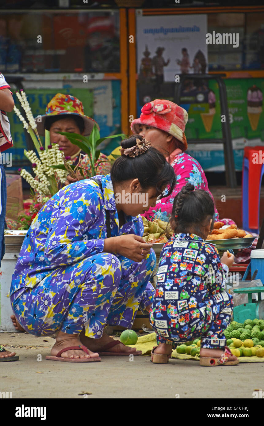 Una madre e figlia indossando pigiami ispezionare frutto nel mercato all'aperto in Kratie, Cambogia Foto Stock