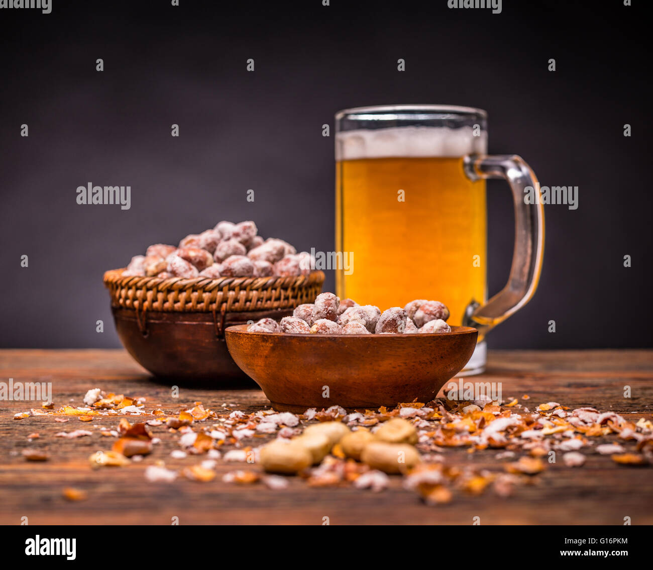 Birra fredda e arachidi tostate sul tavolo di legno Foto Stock