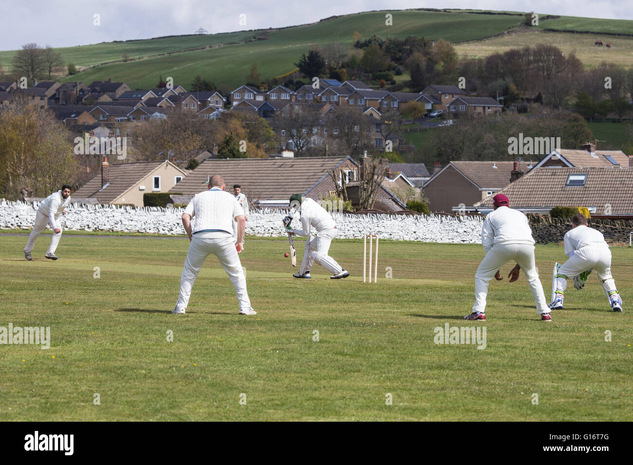 Villaggio Inglese partita di cricket con bowler offrendo la palla a un battitore Foto Stock