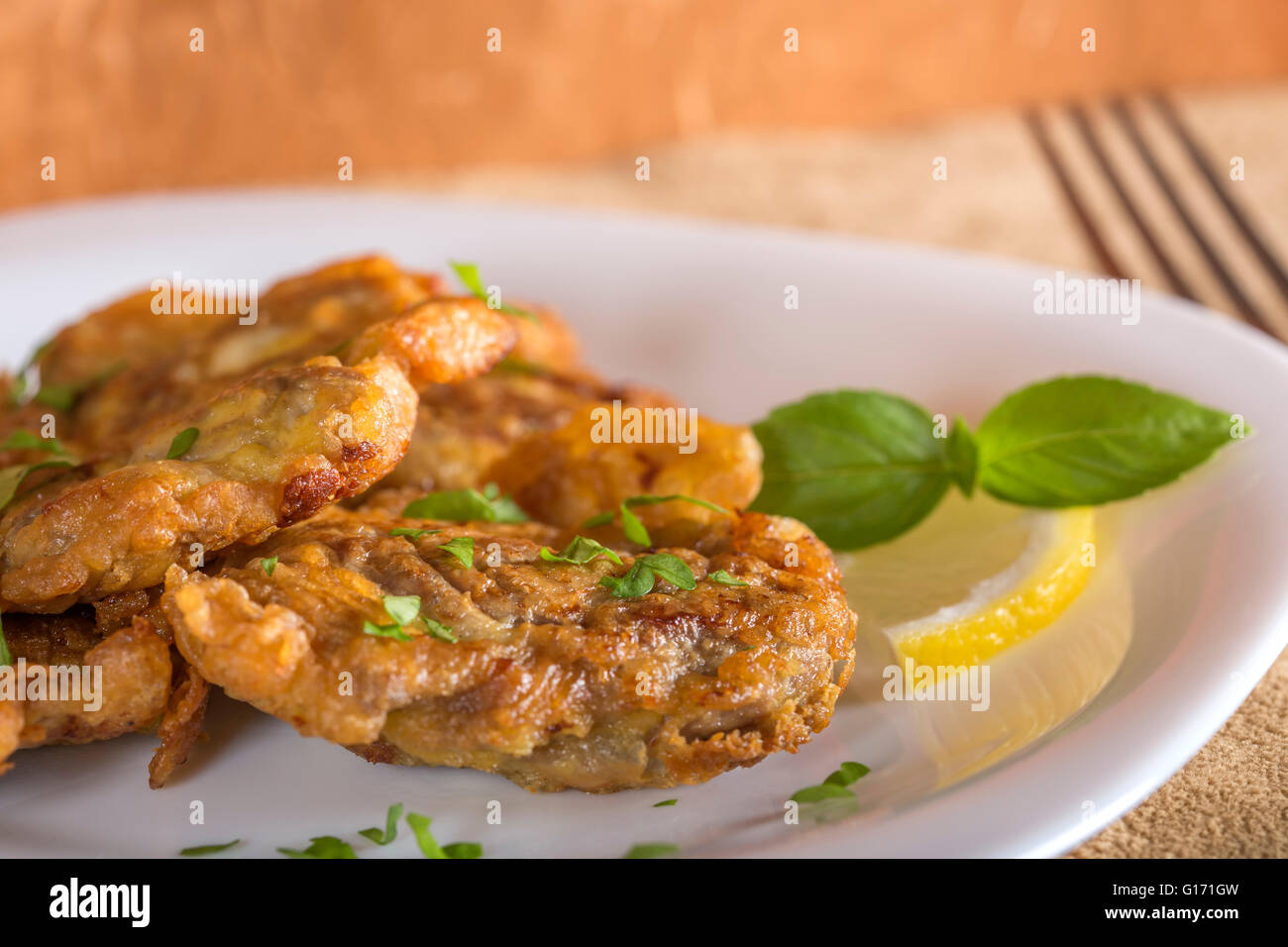 Maiale fritto del cervello con limone e erbe su piastra bianca Foto Stock