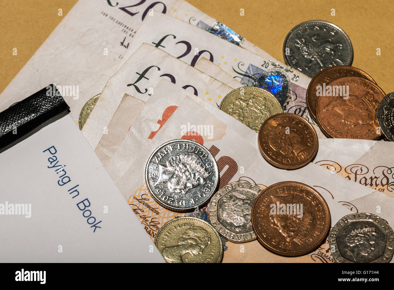 Le banconote e le monete accanto a una banca pagando nel libro Foto Stock