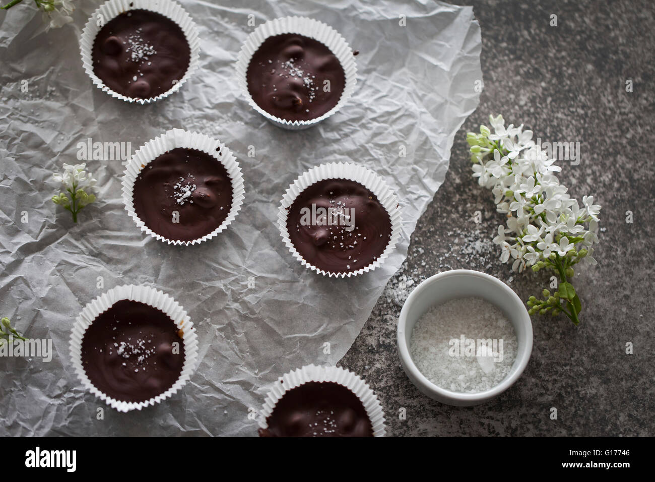 Coppe di cioccolato riempita con data caramello con sale marino su un libro bianco e lo sfondo grigio Foto Stock