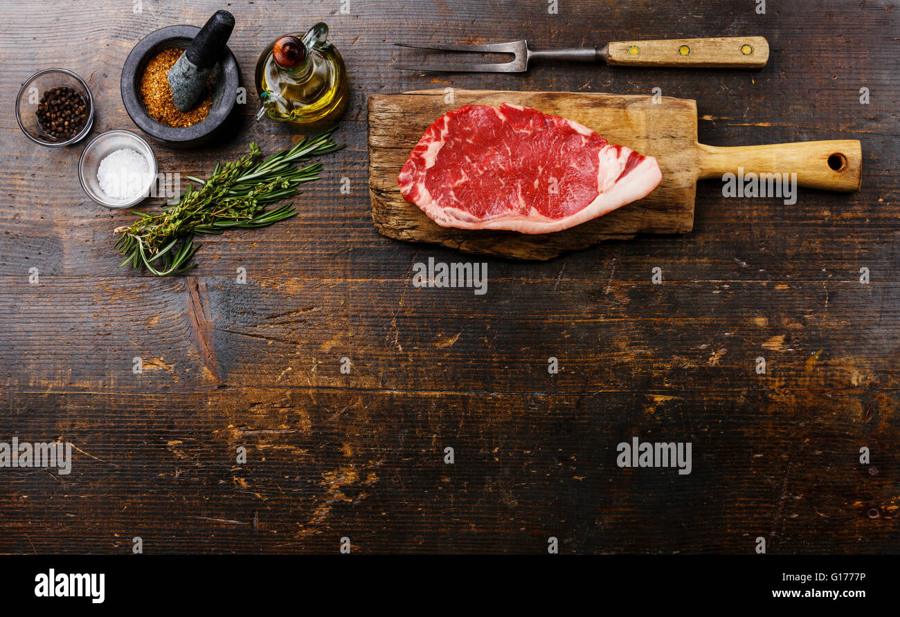 Sfondo di legno con materie di carni fresche Bistecca di controfiletto e ingredienti Foto Stock