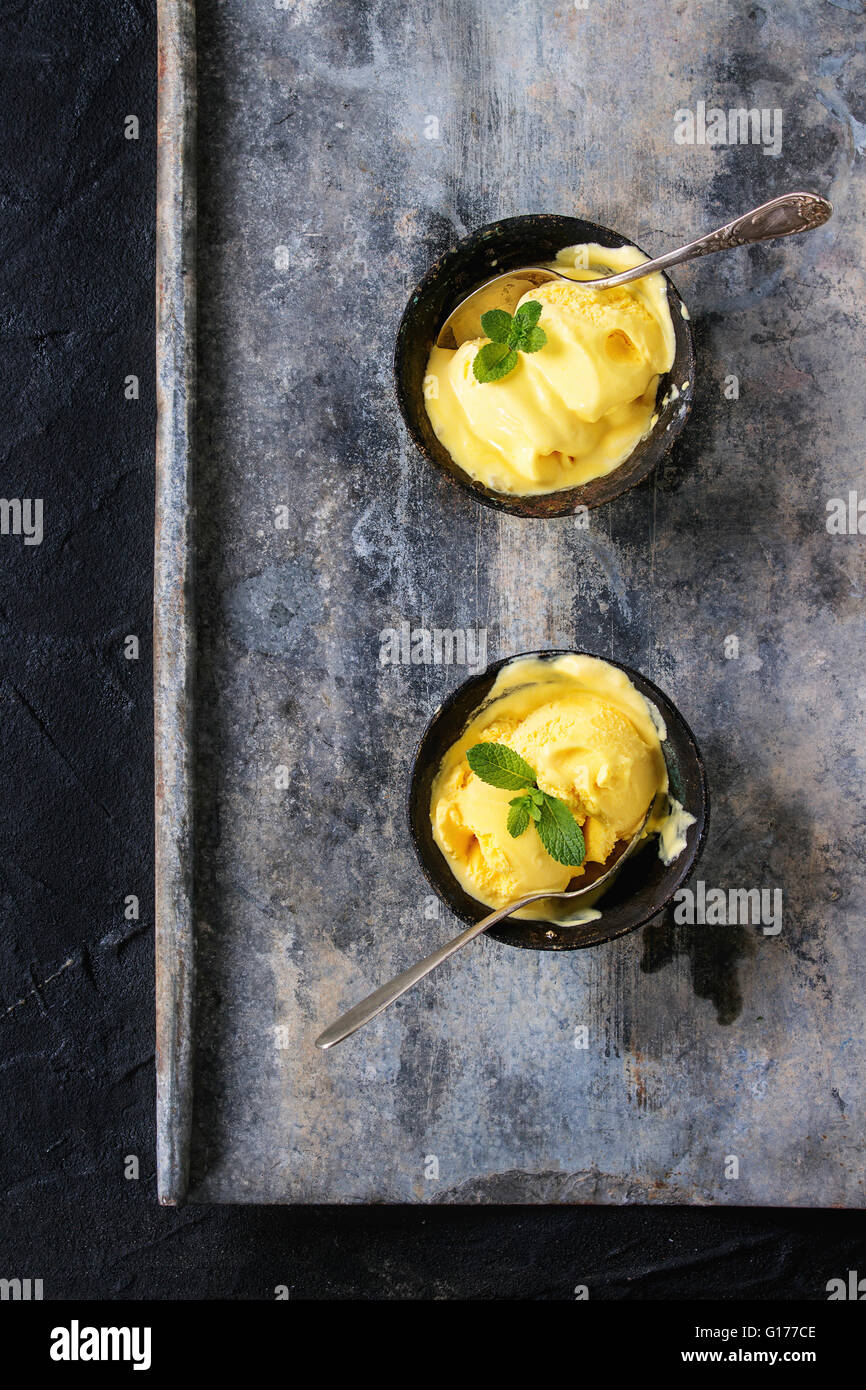 In casa Gelato al mango con menta fresca in ferro vintage bocce su metallo grigio sfondo a trama. Lay piatto Foto Stock