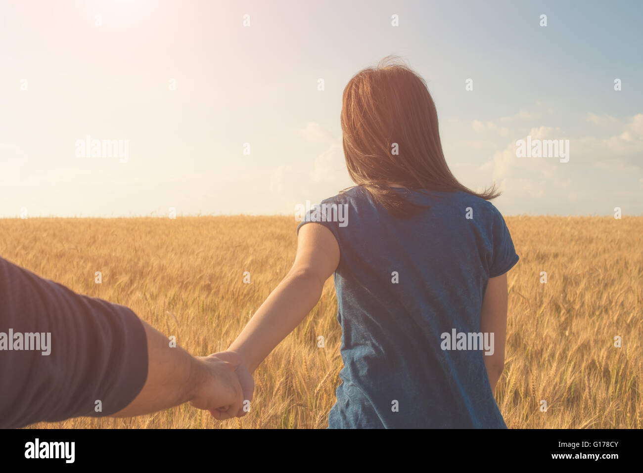 Giovane donna azienda man mano sul campo di grano Foto Stock