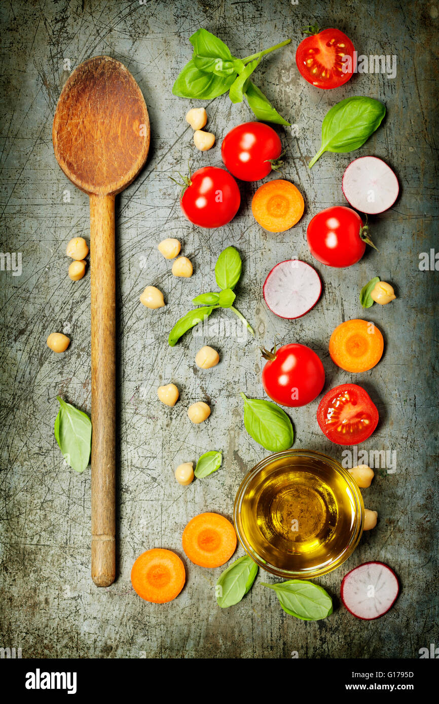 Il cucchiaio di legno e ingredienti freschi sul vecchio sfondo. Cibo vegetariano, la salute o il concetto di cucina a vista. Foto Stock