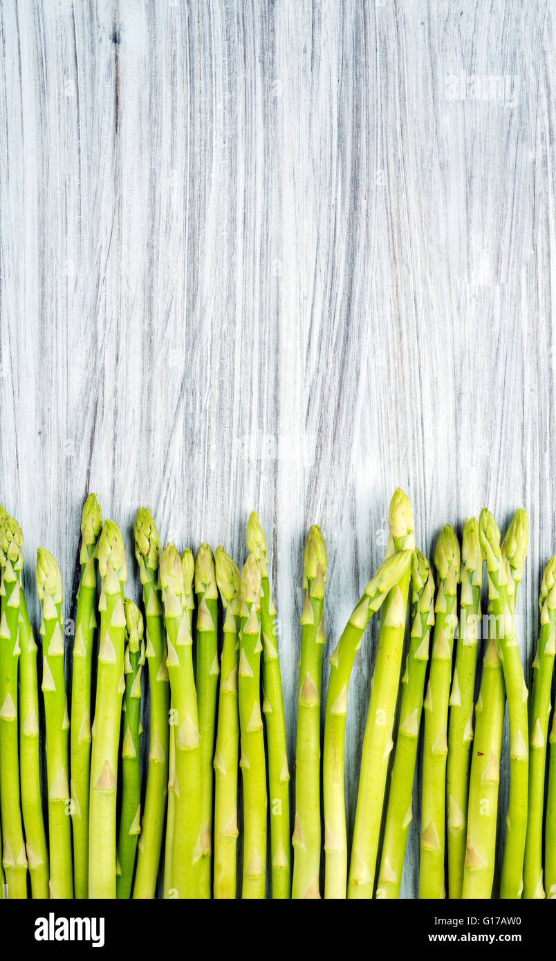 Verde sparagus fresca sulla luce dipinta sullo sfondo di legno. Vista superiore, spazio di copia Foto Stock