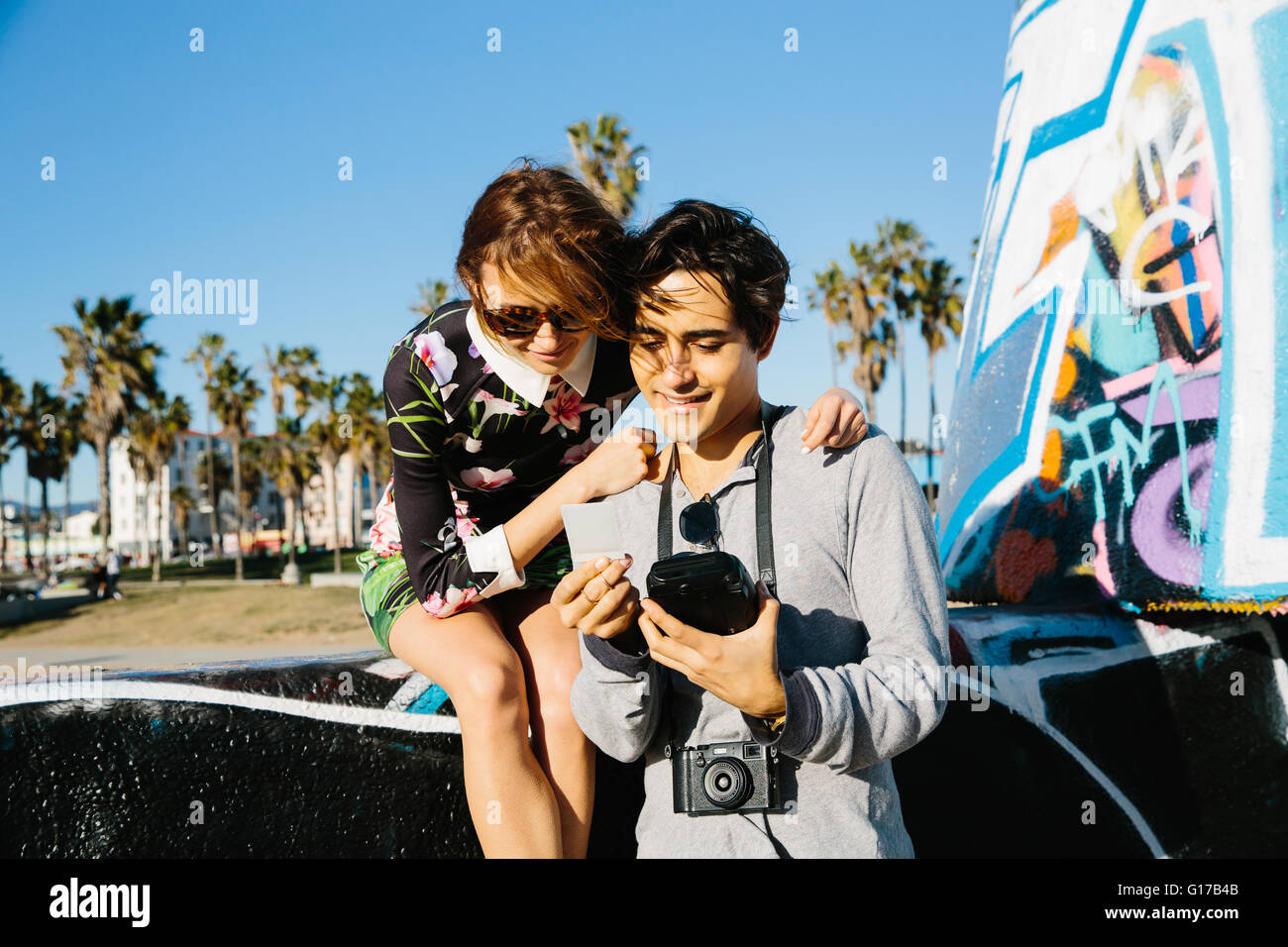 Coppia giovane all'aperto, guardando a pellicola istante fotografia Foto Stock