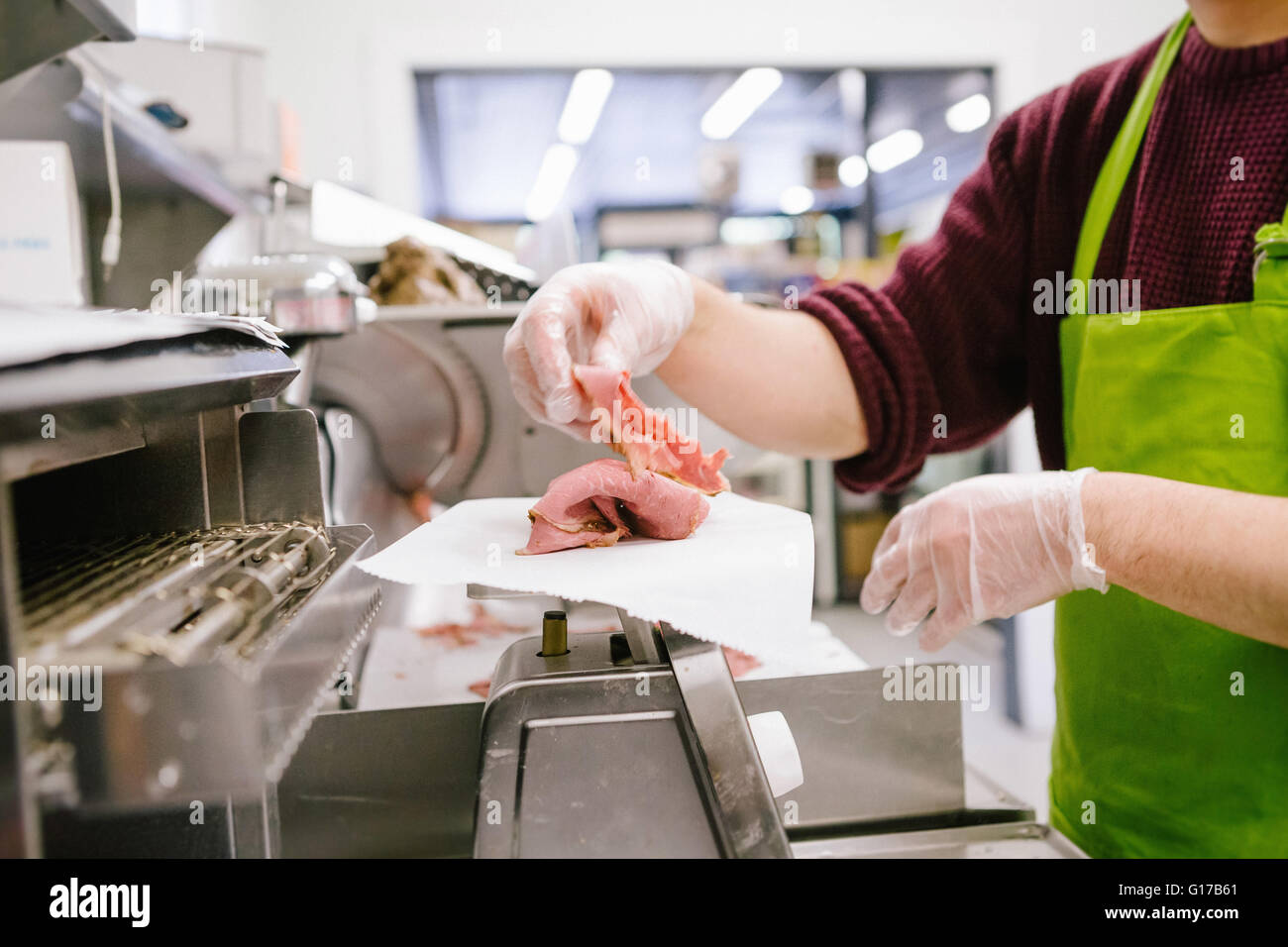 Dipendente nel magazzino generale del peso di carne tagliata a fettine in cucina Foto Stock