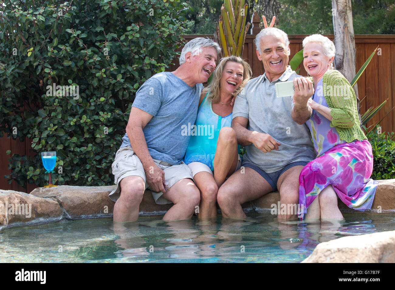 Gruppo di anziani ridere per le foto di smartphone a piscina Foto Stock