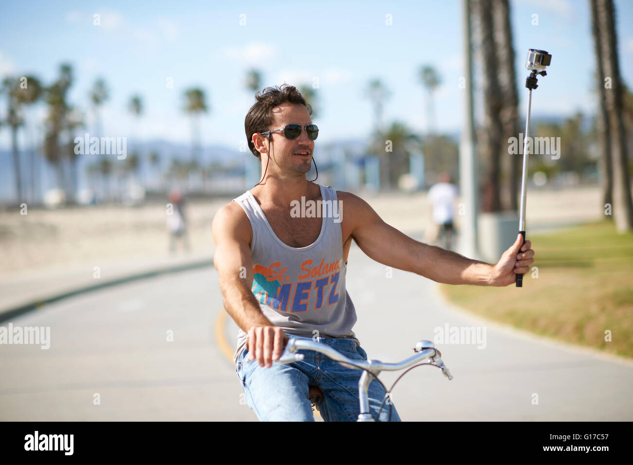 Ciclista maschio facendo ciclismo selfie presso la spiaggia di Venezia, Los Angeles, California, Stati Uniti d'America Foto Stock