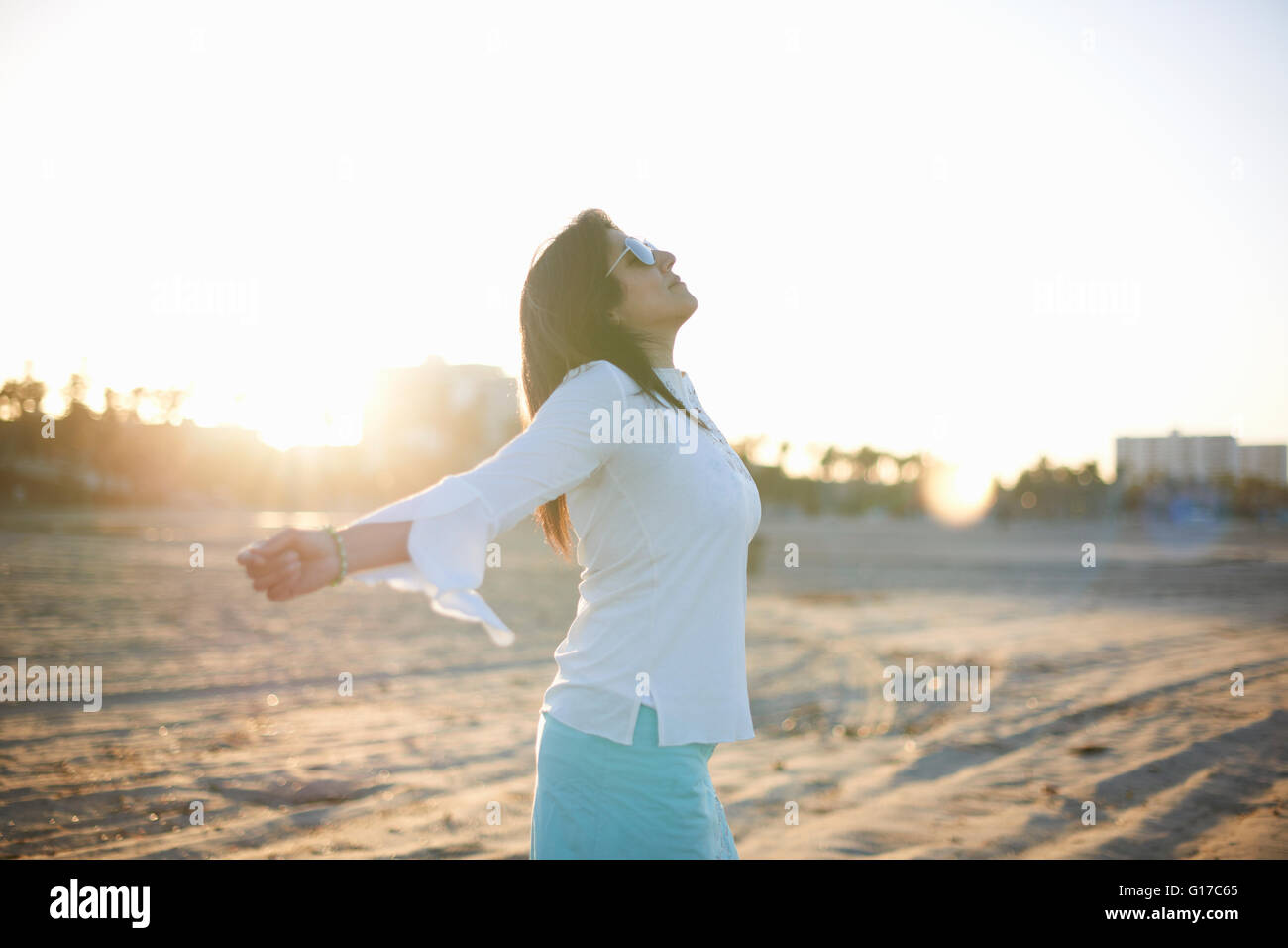 Donna con i bracci aperti sulla spiaggia di Santa Monica al tramonto, Cresent City, California, Stati Uniti d'America Foto Stock