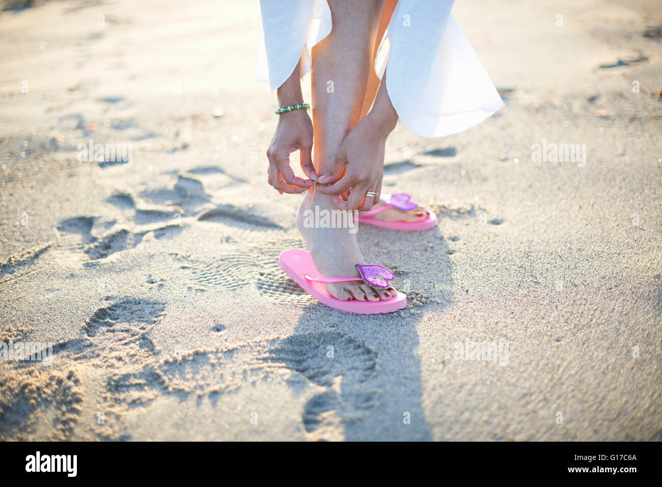 Ritagliato colpo di donna anklet di fissaggio sulla spiaggia di Santa Monica Beach, Cresent City, California, Stati Uniti d'America Foto Stock