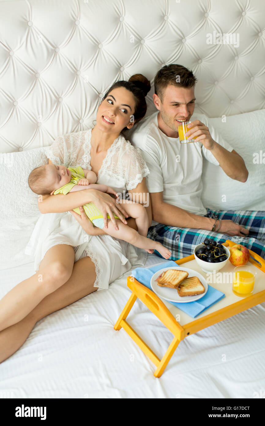 I giovani genitori con baby girl avente la colazione a letto Foto Stock