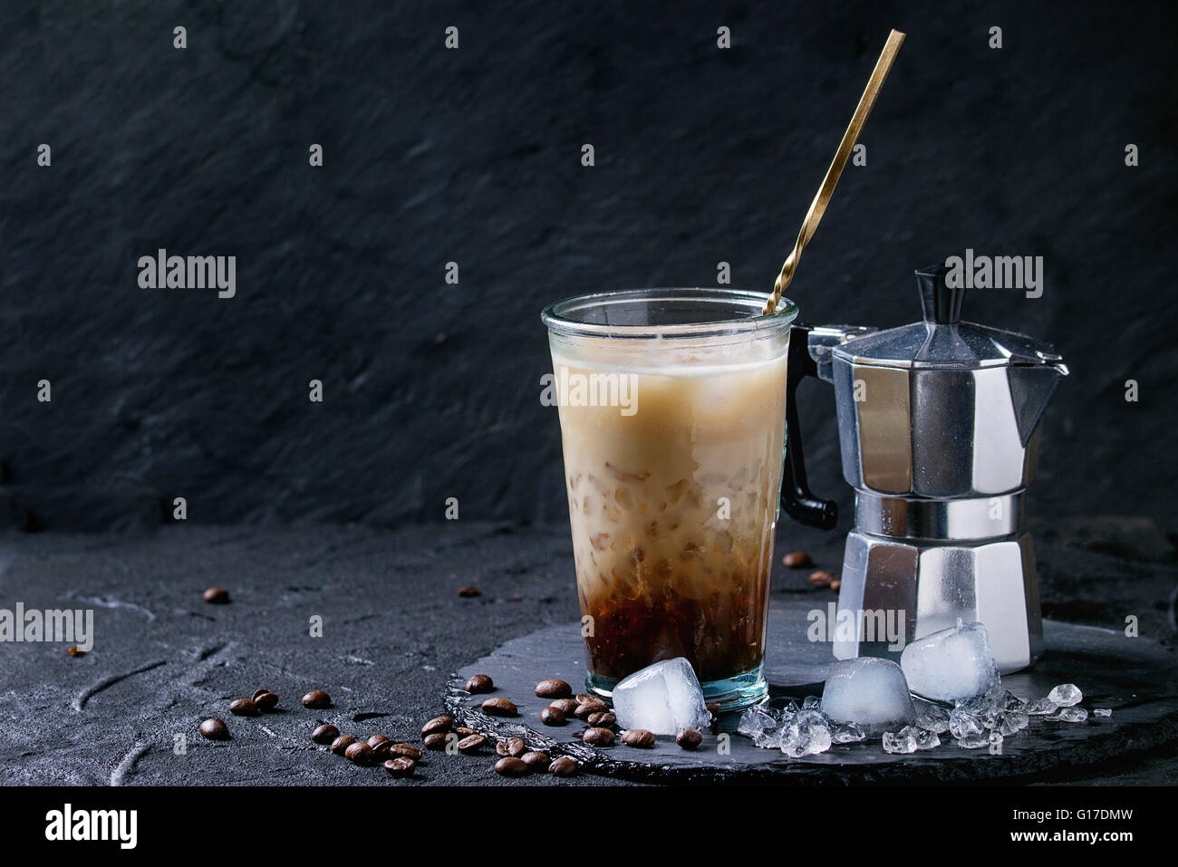 Bicchiere di ghiaccio caffè con panna e latte servita con i chicchi di caffè, i cubetti di ghiaccio e la caffettiera sulla pietra ardesia scheda sopra il testo nero Foto Stock