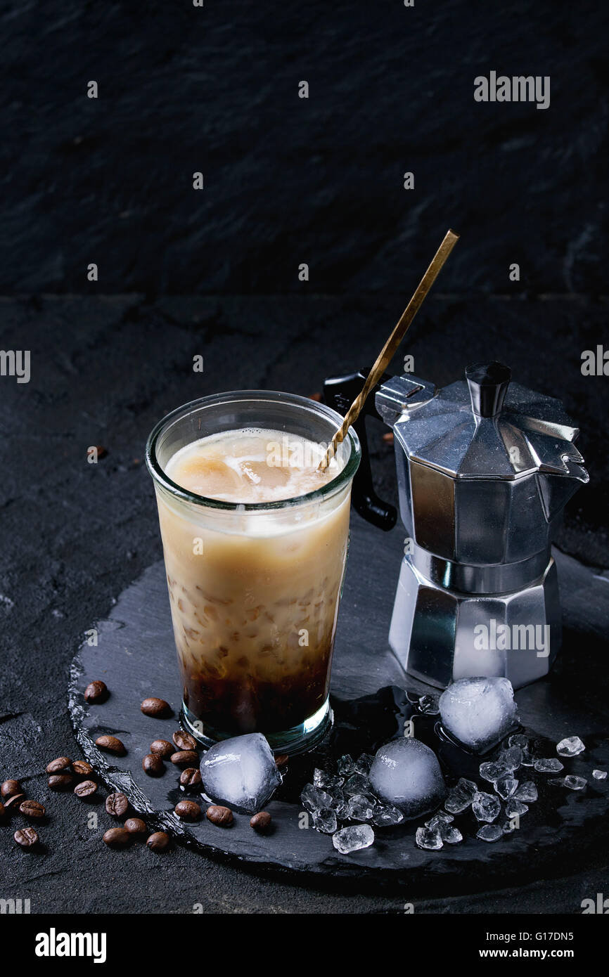 Bicchiere di ghiaccio caffè con panna e latte servita con i chicchi di caffè, i cubetti di ghiaccio e la caffettiera sulla pietra ardesia scheda sopra il testo nero Foto Stock