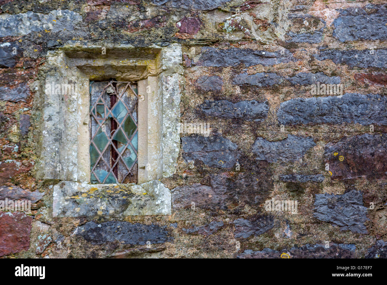 Una vecchia chiesa in pietra con finestre in vetro colorato e condurre il lavoro nel villaggio di Cockington Chiesa, Torquay, Devon, Regno Unito Foto Stock