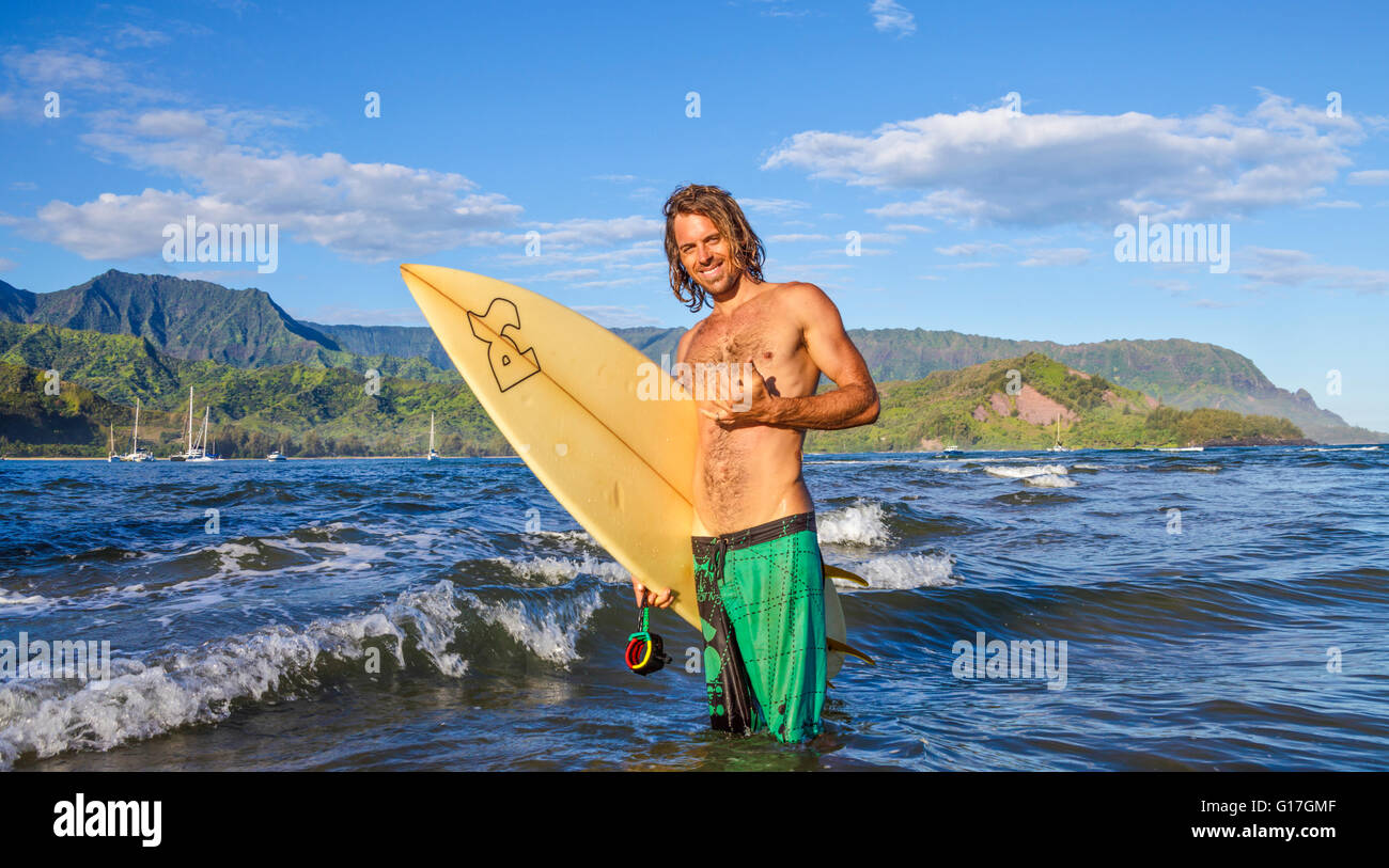 Surfer in Hanalei Bay su Kauai, con Mt. Makana, chiamato Bali Hai, in distanza Foto Stock