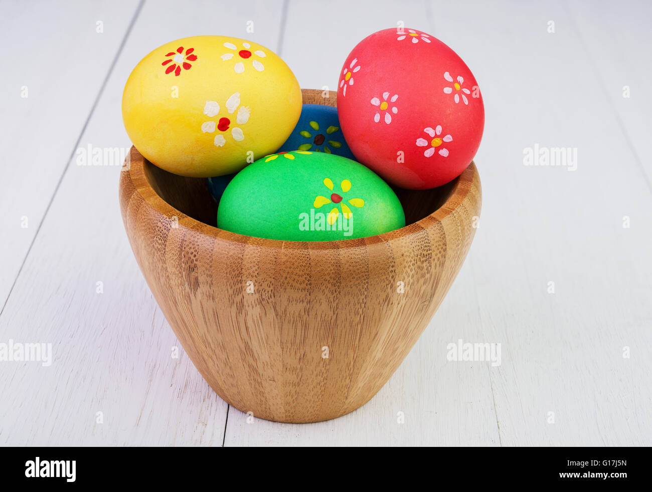 Multicolore di uova di pasqua in ciotola di legno su vintage sfondo di legno Foto Stock