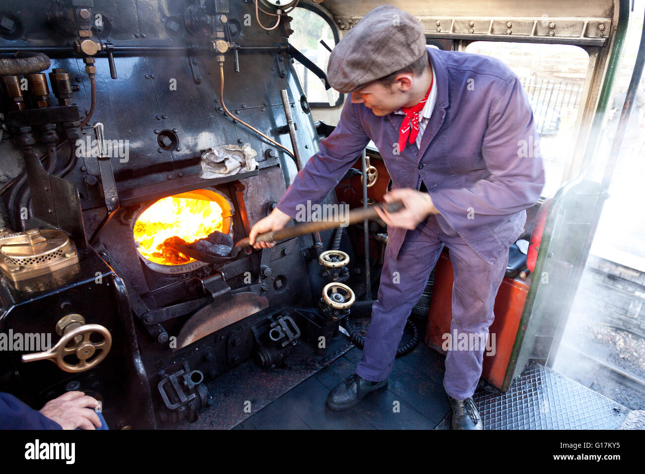 Un vigile del fuoco al lavoro sul pavimento di un ex-BR 9F locomotiva merci sul West Somerset Railway, England, Regno Unito Foto Stock