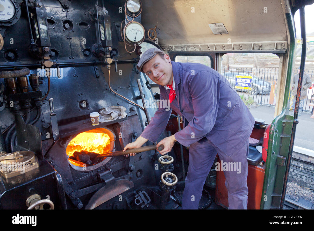 Un vigile del fuoco al lavoro sul pavimento di un ex-BR 9F locomotiva merci sul West Somerset Railway, England, Regno Unito Foto Stock