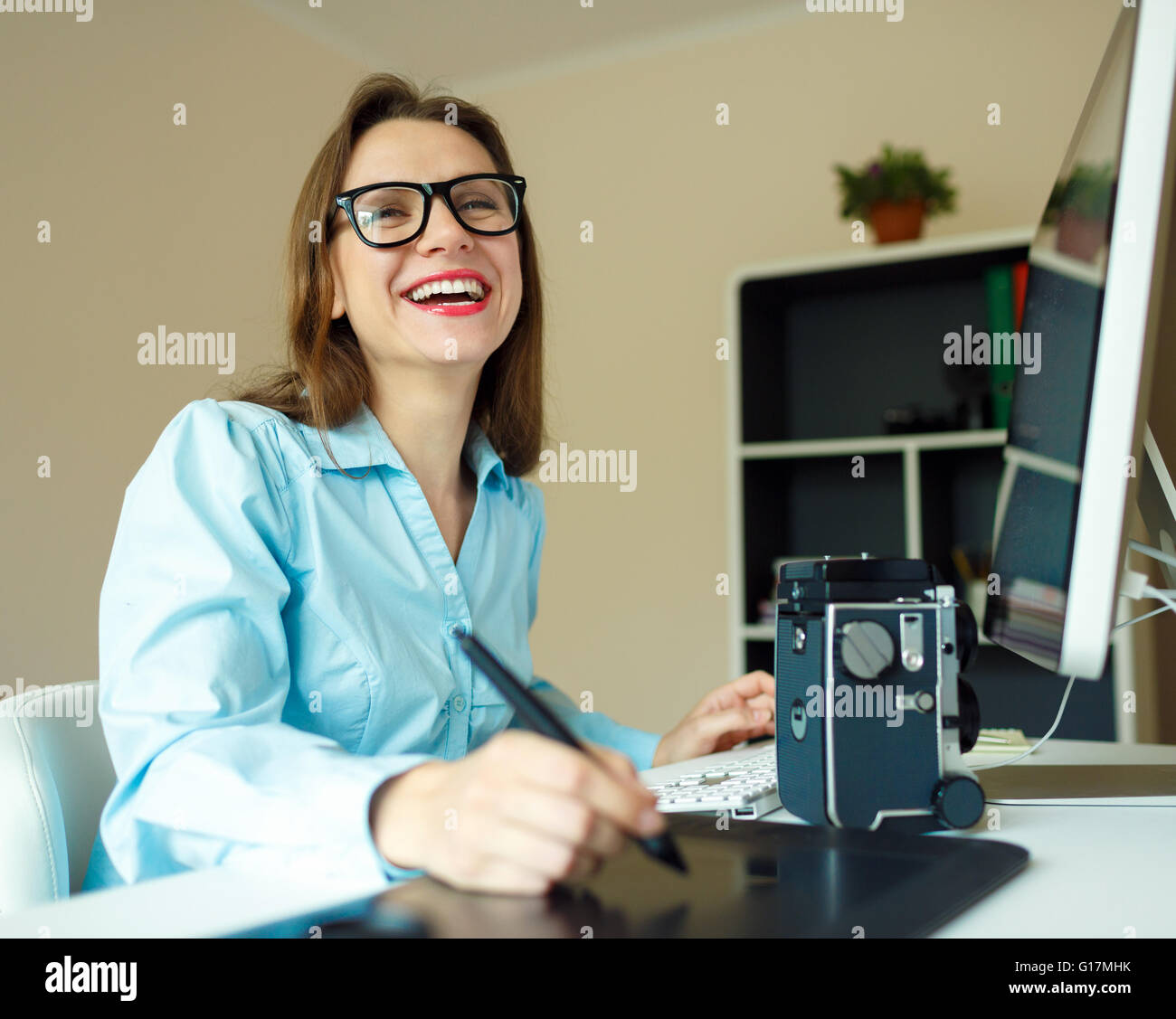 Giovane donna artista disegno qualcosa sulla tavoletta grafica presso l'ufficio a casa Foto Stock