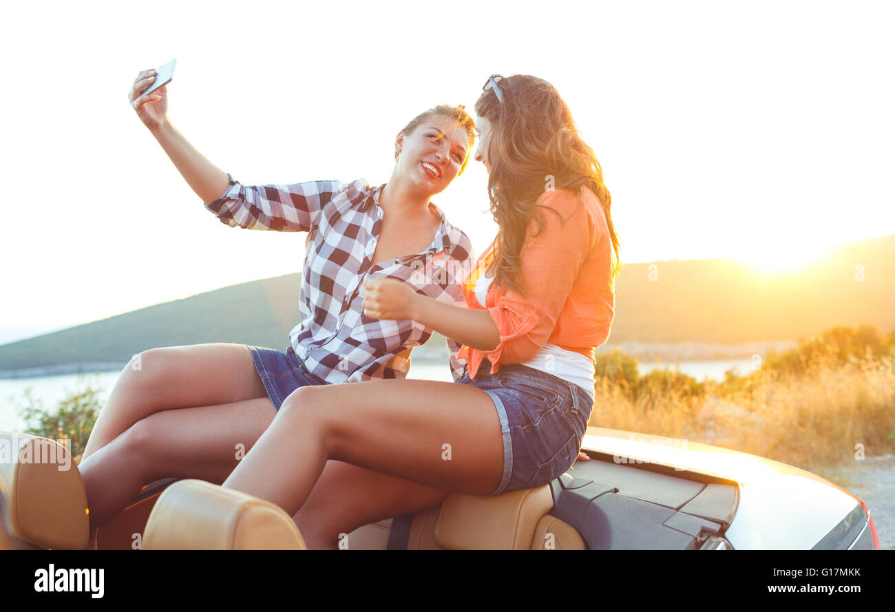 Due giovani belle ragazze stanno facendo una foto di te stesso in una cabriolet Foto Stock