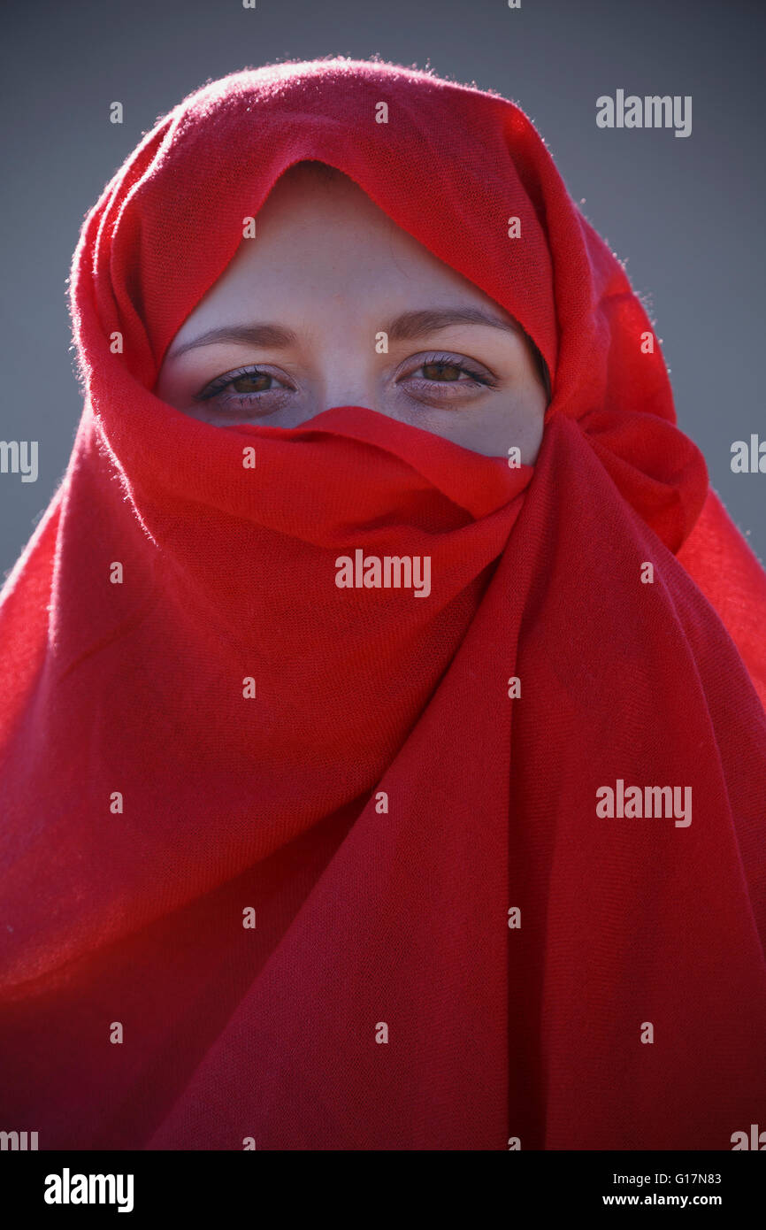 Ritratto di giovane donna indossa velo rosso sul suo viso Foto Stock